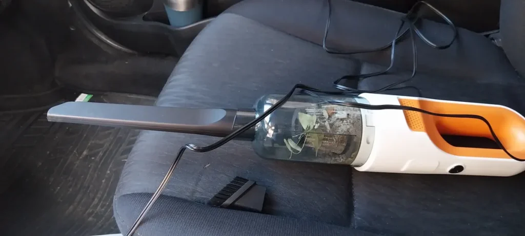 Aspirador de Pó Automotivo 180W Seed.On sendo usado no banco do carro para limpar sujeira, poeira e resíduos internos